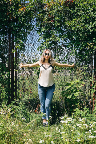 时髦的时髦女孩站在户外常春藤叶墙附近。为年轻女性拍摄时尚照片。金色短发，戴着酷酷的眼镜。图片下载