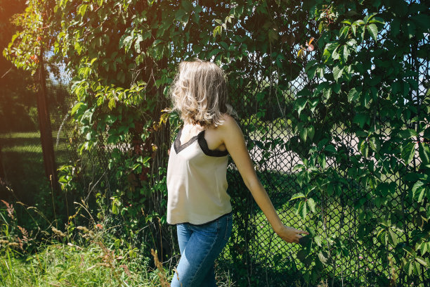 时髦的时髦女孩站在户外常春藤叶墙附近。为年轻女性拍摄时尚照片。金色短发，戴着酷酷的眼镜。夏日生活写真。图片下载