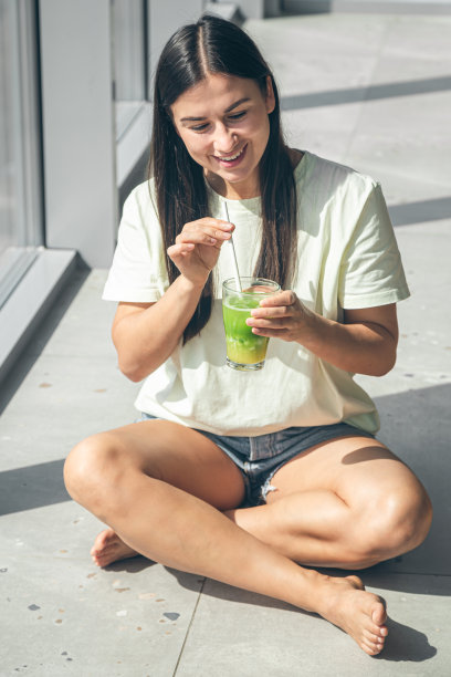 迷人的年轻女子坐在窗边喝着清凉的饮料。图片下载