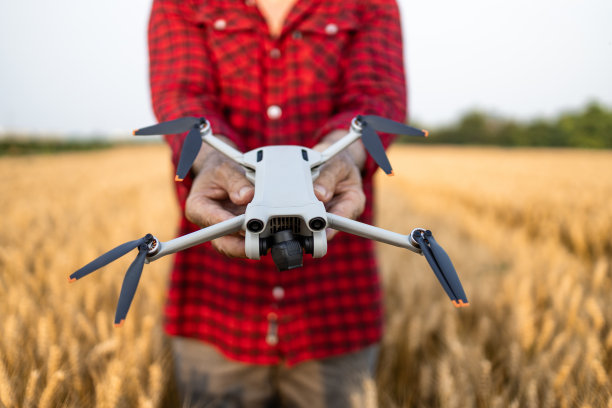 近距离拍摄的一名无法辨认的农民手持农业无人机监控农田里的作物。图片下载