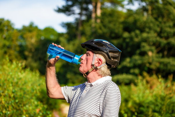 在森林小道上，骑自行车的年长男性正在用水瓶喝水图片下载