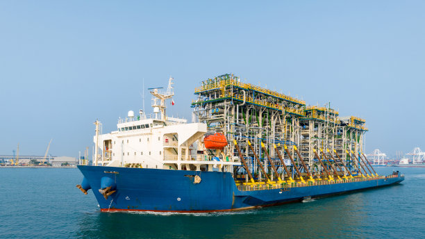 日落时分，驳船运输平台上的招标钻井平台到海洋中央的石油钻井平台。驳船运输油网的大型设备。图片下载