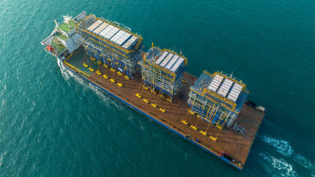 日落时分，驳船运输平台上的招标钻井平台到海洋中央的石油钻井平台。驳船运输油网的大型设备。图片下载