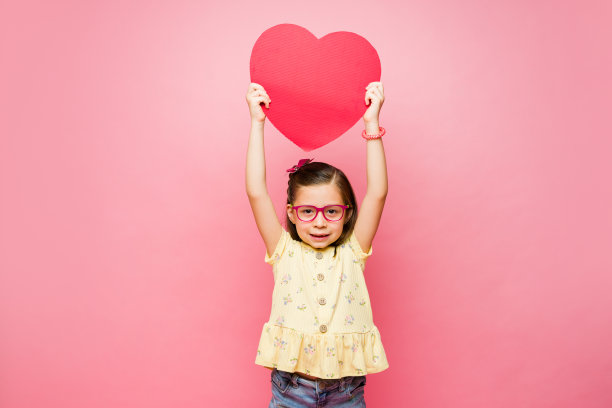 可爱的小男孩表现出一颗红色的心图片下载