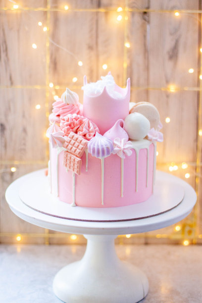 粉色公主蛋糕，在节日的背景下，有糖冠、棉花糖、马卡龙、冰棍和棒棒糖图片下载