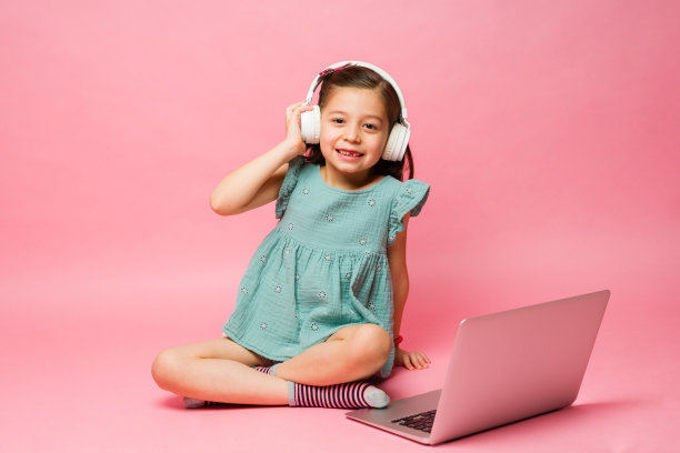 快乐的小学生在用带耳机的笔记本电脑图片下载