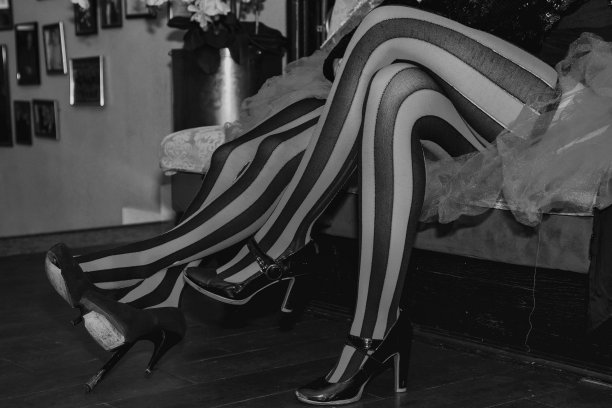 马戏团女演员的特写，穿着红黑条纹丝袜，坐在更衣室里。黑白照片的戏剧女士的腿。剧场表演概念。复制广告文本空间横幅图片下载
