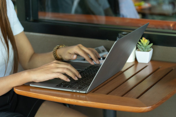 商务女性坐在办公桌前，带着专业的表情，手里拿着平板电脑，偶尔喝一口咖啡，专心地摆弄着手机。有效地处理她的任务。图片下载