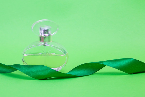 绿色背景上的香水。香水和礼物丝带。带有喷雾的复古香水。图片下载