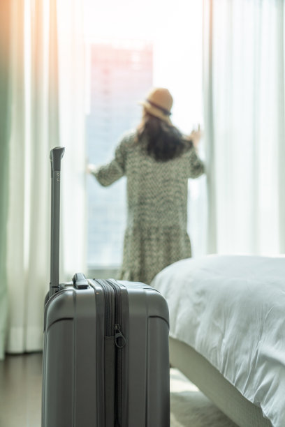 在商务酒店的客房里，带着行李的旅行者向外看城市景观，适合工作旅行或度假旅行图片下载
