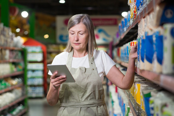 店内资深有经验的女员工清点货物，使用平板电脑图片下载