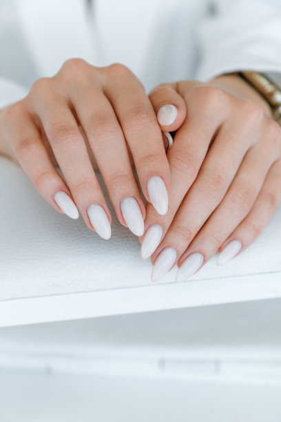 指甲护理概念。垂直特写照片，一个美丽的女人双手展示完美的指甲，涂着裸色指甲油在指甲沙龙图片下载
