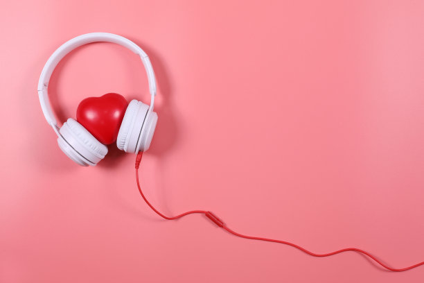 白色耳机与红色的心孤立在粉红色的背景，平铺摄影有复制空间。图片下载