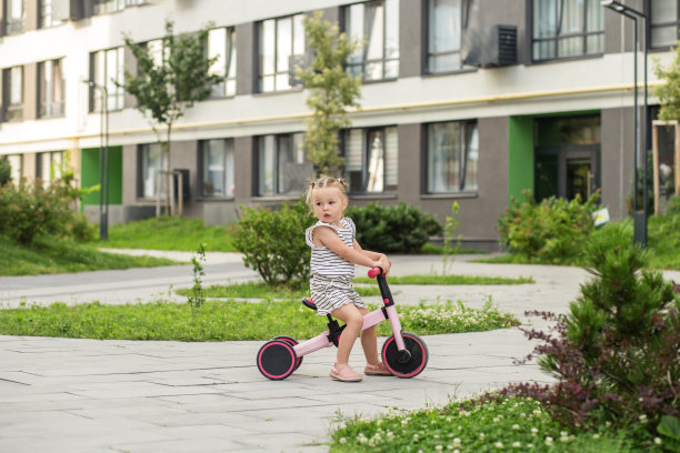 蹒跚学步的女孩在户外骑平衡自行车。学习骑自行车的概念。图片下载