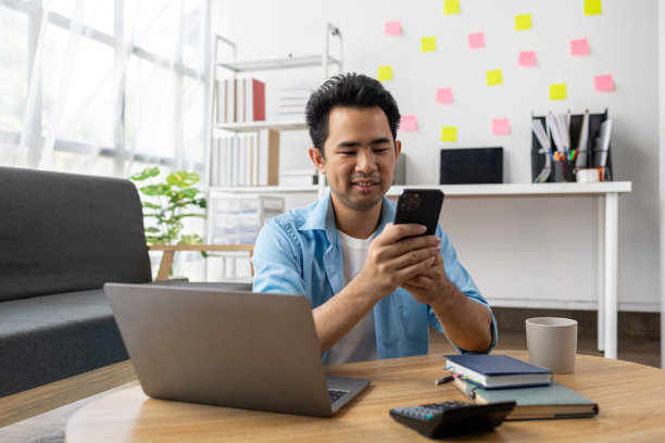 亚洲男子拿着手机，他正在通过智能手机应用程序与朋友聊天，用智能手机在互联网上发送短信。在通信中使用技术的概念。图片下载