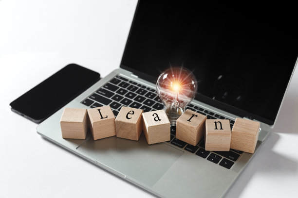 木块立方体与文本学习与灯泡明亮的光耀斑在笔记本电脑上。思考创造性创新。电子商务在线头脑风暴，学习愿景和理念。图片下载