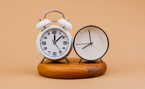 现代闹钟摆放在木质平面上，有时间闹钟、通知、闹钟和工作的概念图片下载