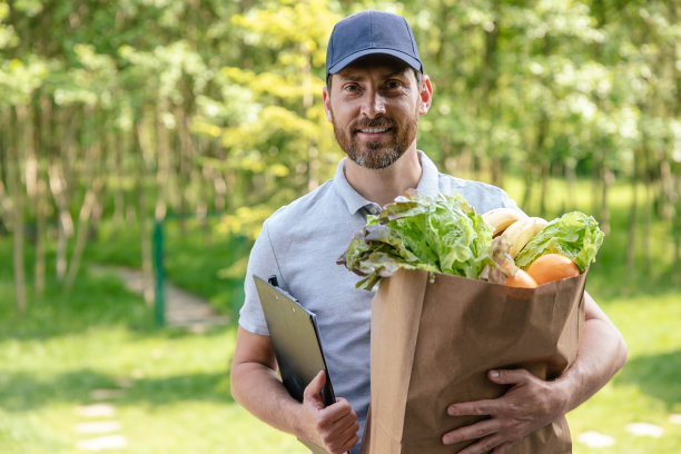 帅气的快递员从商店里拿着一箱食品。图片下载