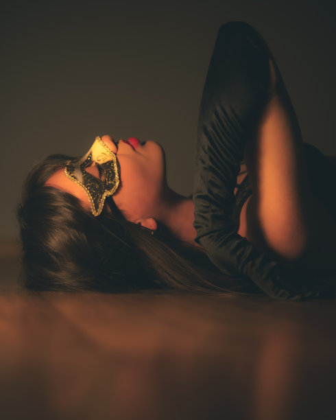 假面舞会的意大利女人在柔和温暖的灯光下，在木质地板上摆姿势。图片下载