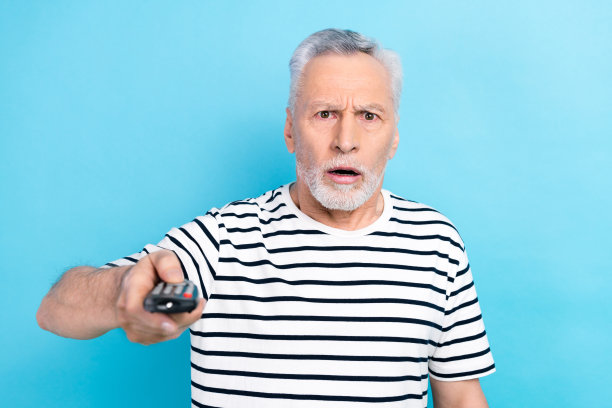 震惊的男人穿着时髦的衣服，在蓝色的背景下看恐怖电影图片下载