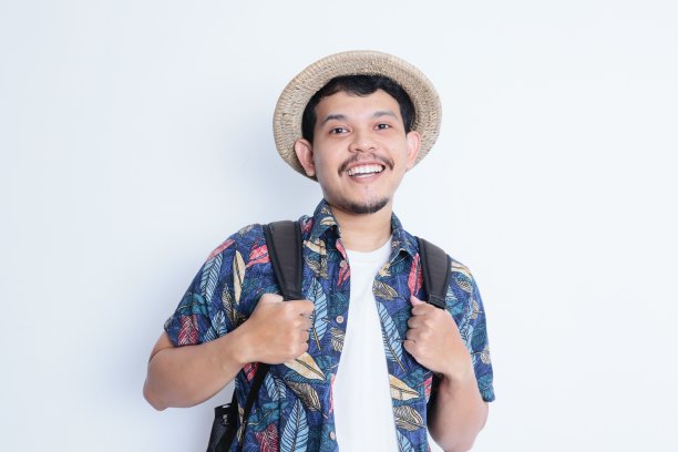 一个穿着沙滩装的年轻人对着镜头微笑。度假旅游理念图片下载