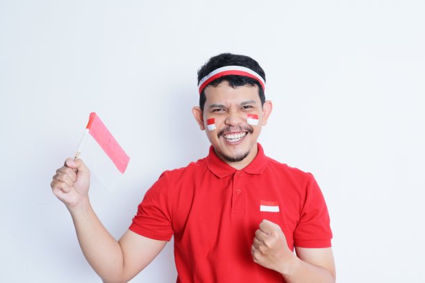 印度尼西亚一名男子握紧拳头，手持红白相间的旗帜，在庆祝独立日时表现出兴奋图片下载