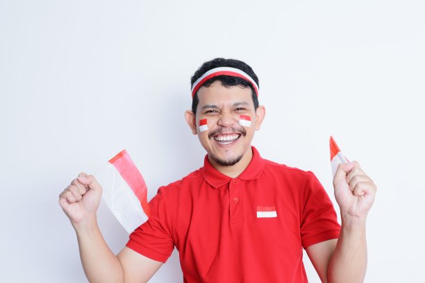 印度尼西亚一名男子握紧拳头，手持红白相间的旗帜，在庆祝独立日时表现出兴奋图片下载