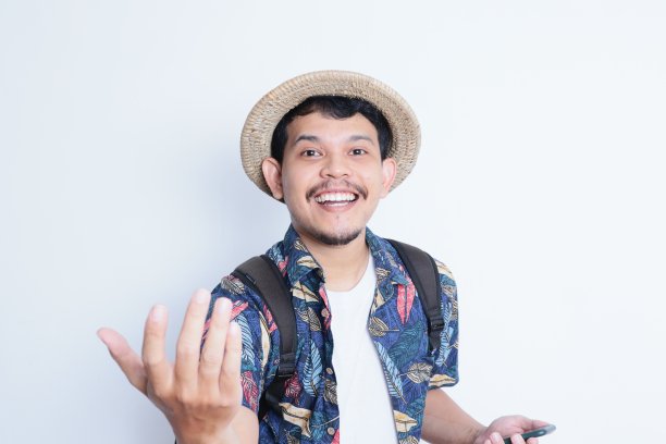 一个穿着沙滩装的年轻人的肖像，微笑着对着镜头做出“放手”的手势。度假旅游理念图片下载