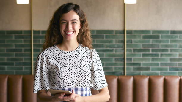 咖啡店或餐厅里微笑的女老板或员工拿着数码平板电脑的肖像图片下载