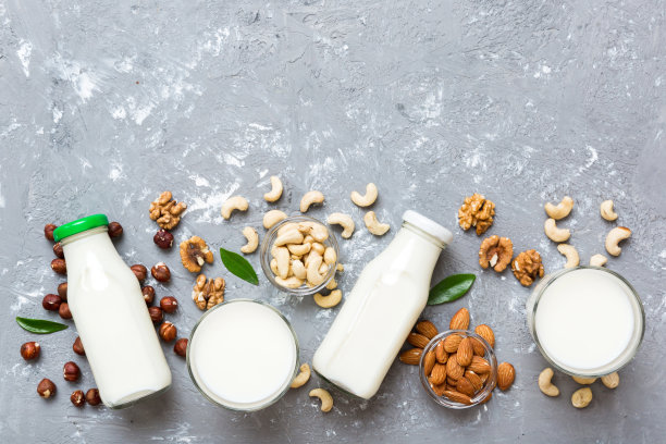集或收集各种纯素牛奶杏仁，腰果，在桌子的背景。素食植物奶和原料，俯视图图片下载