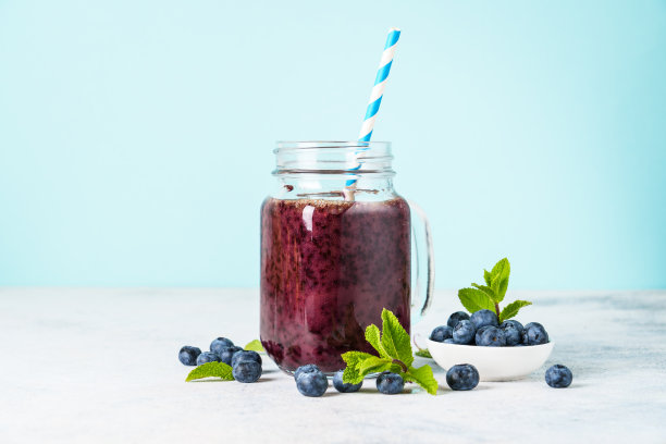 蓝莓冰沙与新鲜的浆果在蓝色背景。图片下载