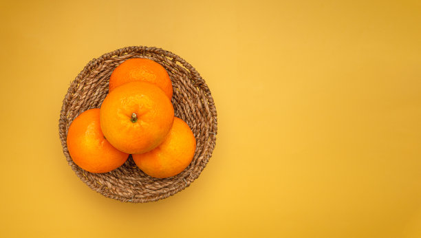 黄色背景上篮子里的新鲜橙子俯视图图片下载