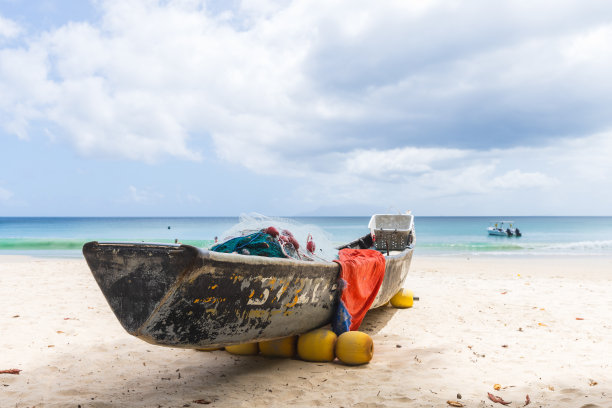 塞舌尔博瓦隆海滩的沙滩上，一艘旧渔船上挂着渔网图片下载