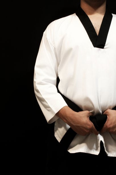 一个强壮的男性运动员的一半身体，白色的头巾，黑色的腰带，孤立在黑色的背景在右边图片下载