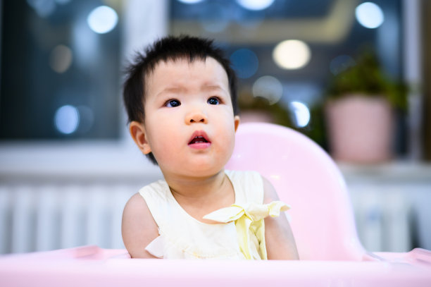 亚洲可爱的小婴儿坐在餐厅的婴儿餐椅上图片下载