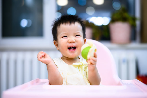 亚洲可爱的小婴儿坐在餐厅的婴儿餐椅上图片下载