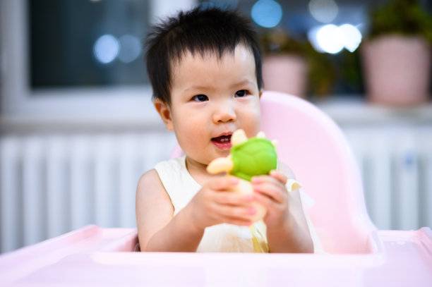 亚洲可爱的小婴儿坐在餐厅的婴儿餐椅上图片下载