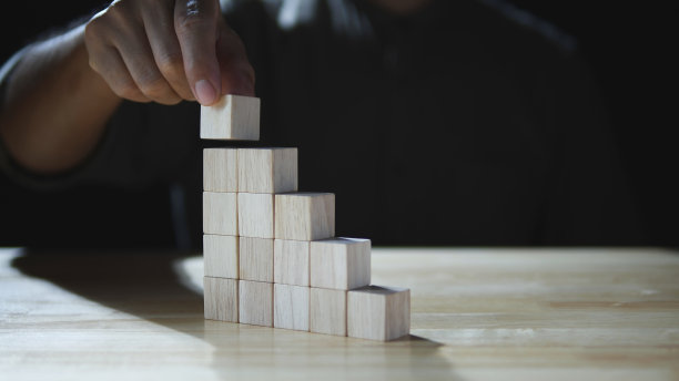 商人手中堆砌的木块如同台阶台阶，企业发展，企业成长成功，背景阴暗。业务增长的概念，财务规划，投资，战略图片下载