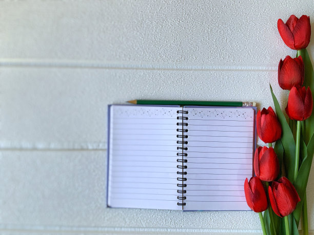 美丽的红色郁金香与笔记本和铅笔在白色的背景图片下载