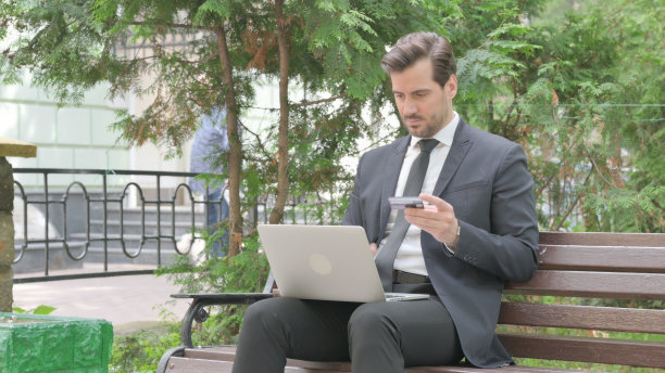 中年商人为在户外笔记本电脑上成功网购而兴奋图片下载