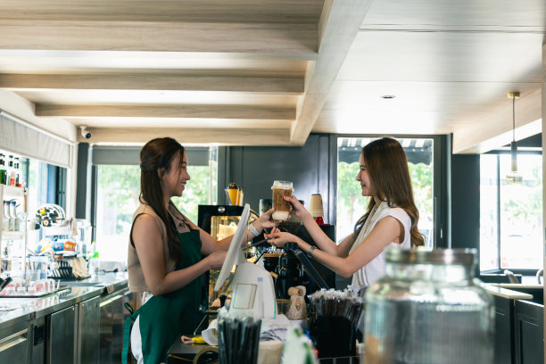 微笑的亚洲咖啡师自豪地在咖啡店提供咖啡图片下载