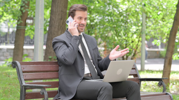 年轻的商人在户外打电话和使用笔记本电脑图片下载
