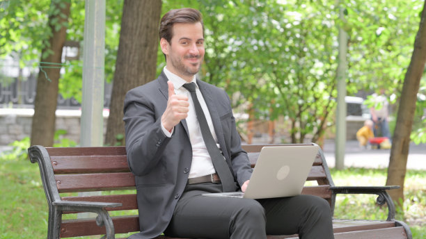 年轻的商人对笔记本电脑户外竖起大拇指图片下载