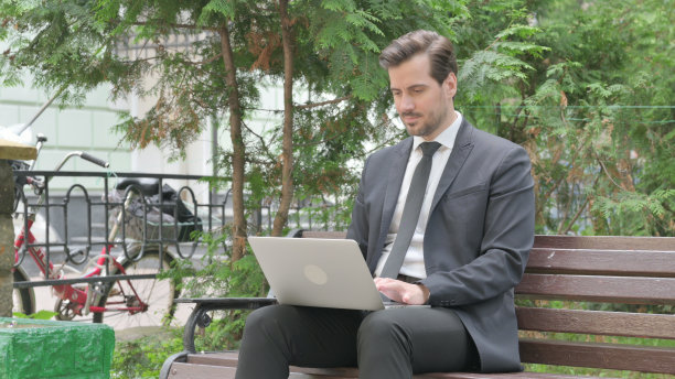 中年商人在户外用笔记本电脑工作图片下载