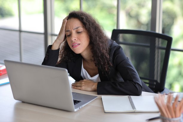 中年商业女性在遇到坏消息，生意失败或被解雇后，在办公室里把头靠在桌子上，在现代办公室里感到沮丧、心烦意乱和绝望。图片下载