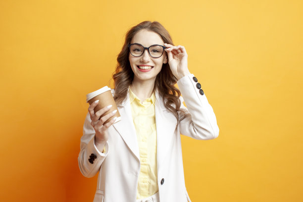 办公室的风格。身穿白色西装的女商人端着一杯咖啡，戴上了眼镜图片下载