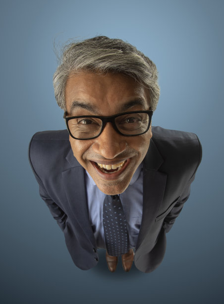 成功的高级男性企业家穿着西装站在蓝色背景的高角度视图图片下载