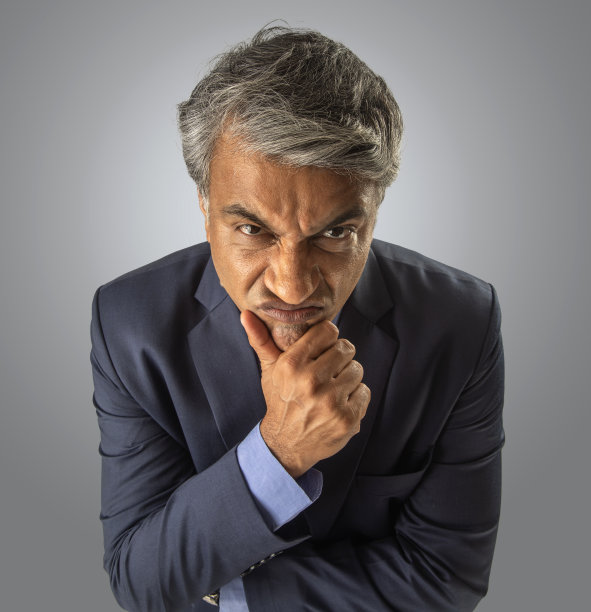 愤怒的资深商人在白色背景上触摸下巴图片下载