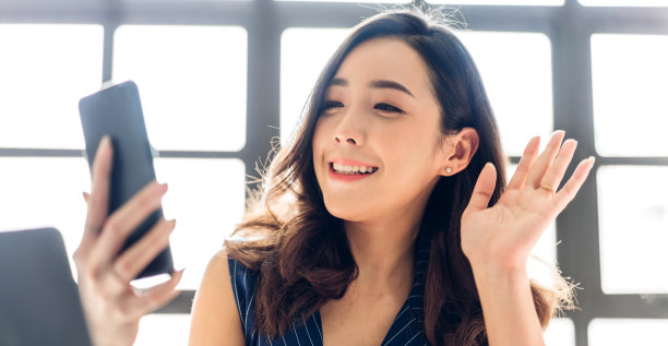 微笑幸福美丽的亚洲女人的肖像放松使用数字智能手机。年轻的亚洲女孩盯着屏幕打字，在家玩在线游戏或社交媒体图片下载