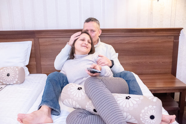 男人和女人在床上看电视。图片下载